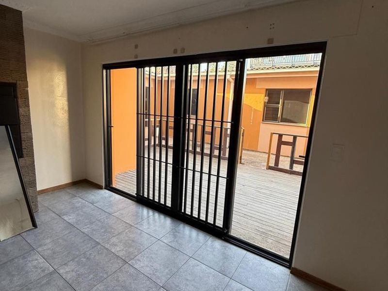 An empty living room featuring tiled flooring, a fireplace, and large sliding glass doors that open onto an outdoor deck area.