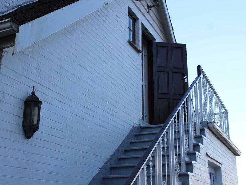 Exterior view of an apartment featuring an external staircase with wrought iron balustrades and a painted brick facade.