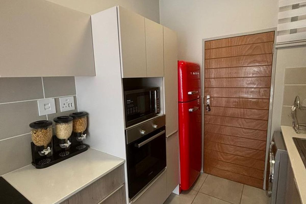 Modern kitchen featuring built-in cabinetry, integrated oven, microwave, and tiled flooring, providing a functional and contemporary cooking space.