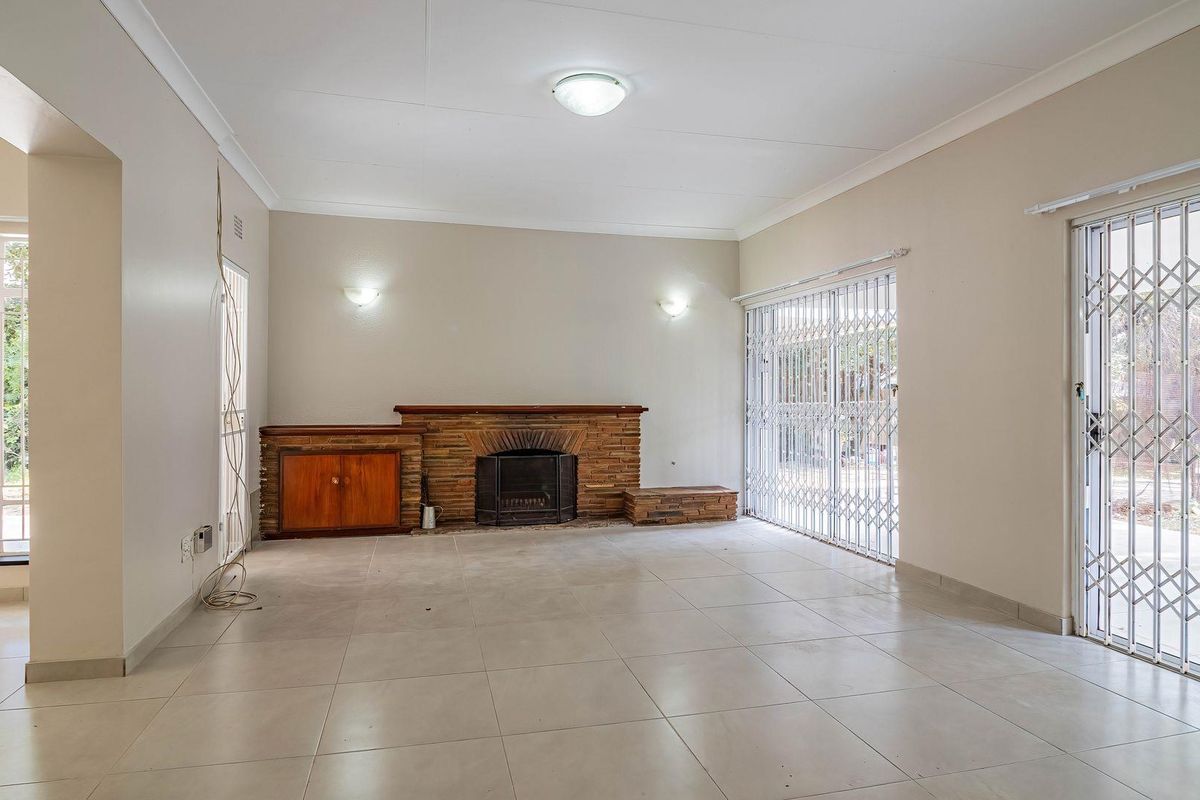 Spacious living room featuring tiled flooring, a built-in stone fireplace with integrated cabinetry, and security gates on sliding glass doors.