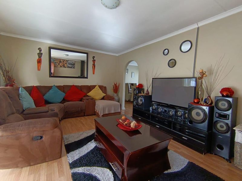 A comfortable living room featuring laminate flooring, coved ceilings, and an arched doorway leading to adjacent living spaces.