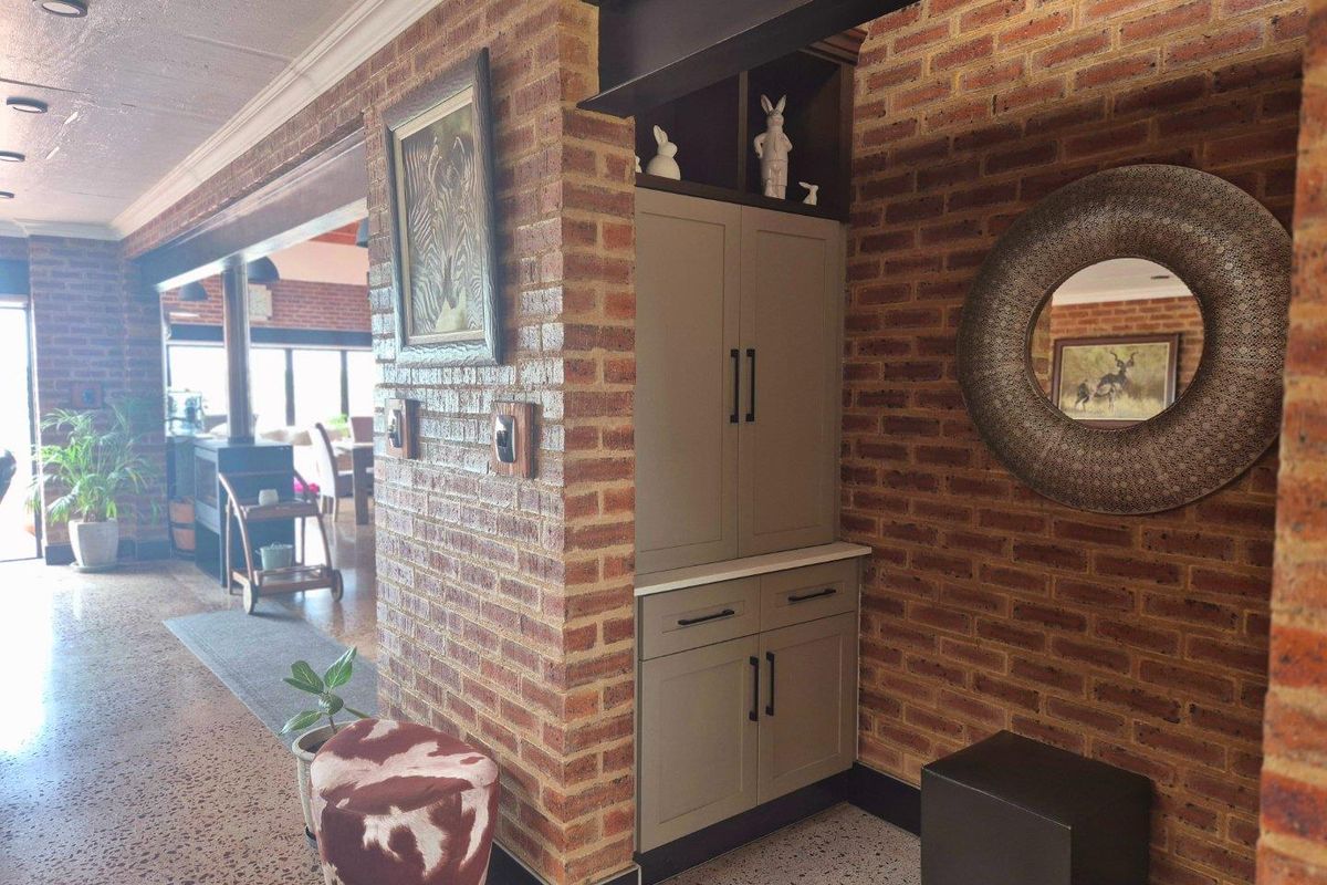 A living area featuring exposed brick walls, terrazzo flooring, and custom built-in cabinetry, showcasing a blend of industrial and classic architectural elements.