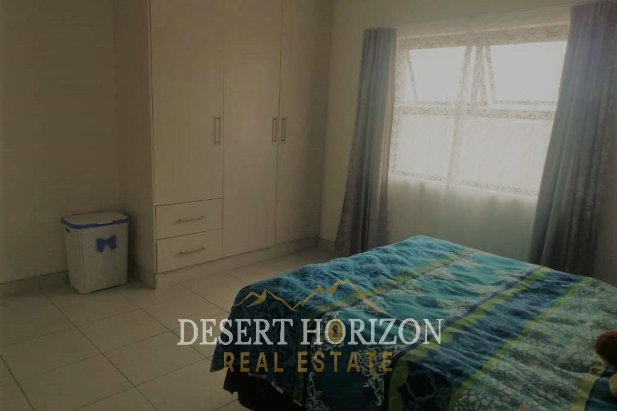 A functional bedroom featuring built-in cupboards and tiled flooring, providing ample storage space and a neutral foundation for personalization.