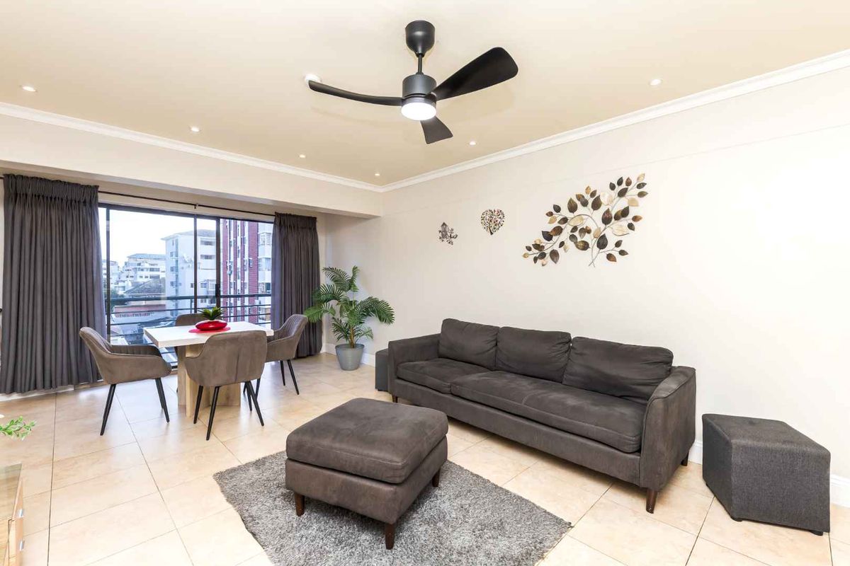 A well-maintained living area featuring tiled flooring, recessed lighting, a modern ceiling fan, and large sliding glass doors leading to an outdoor space.