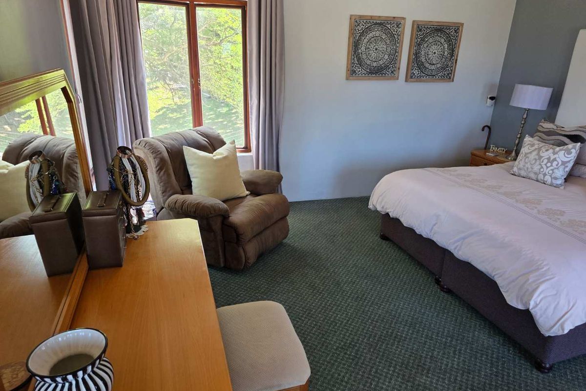A spacious bedroom featuring carpeted flooring, large windows with natural light, and neutral wall finishes.
