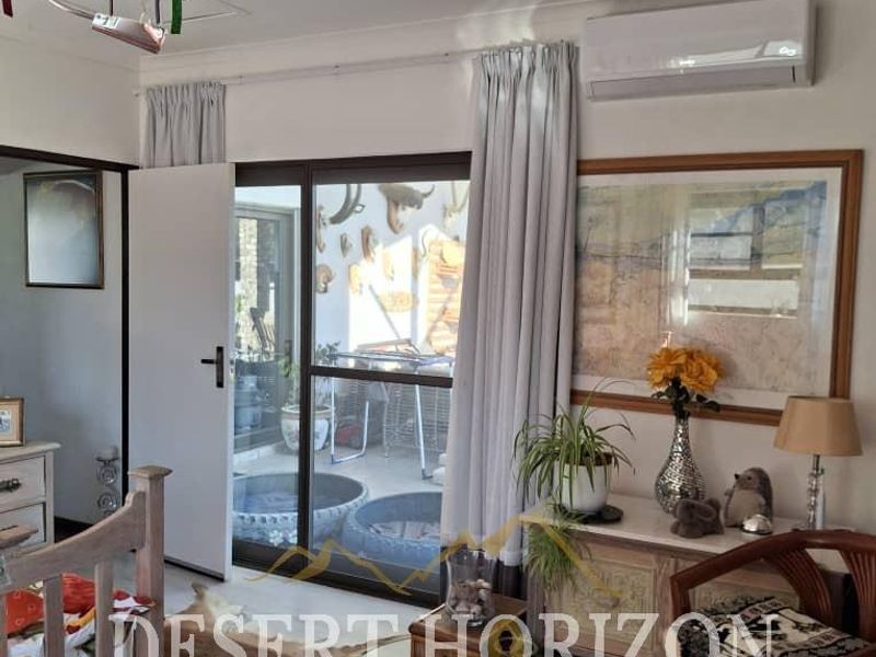 A bedroom featuring laminate flooring, a wall-mounted air conditioning unit, and a sliding glass door providing access to an outdoor area.