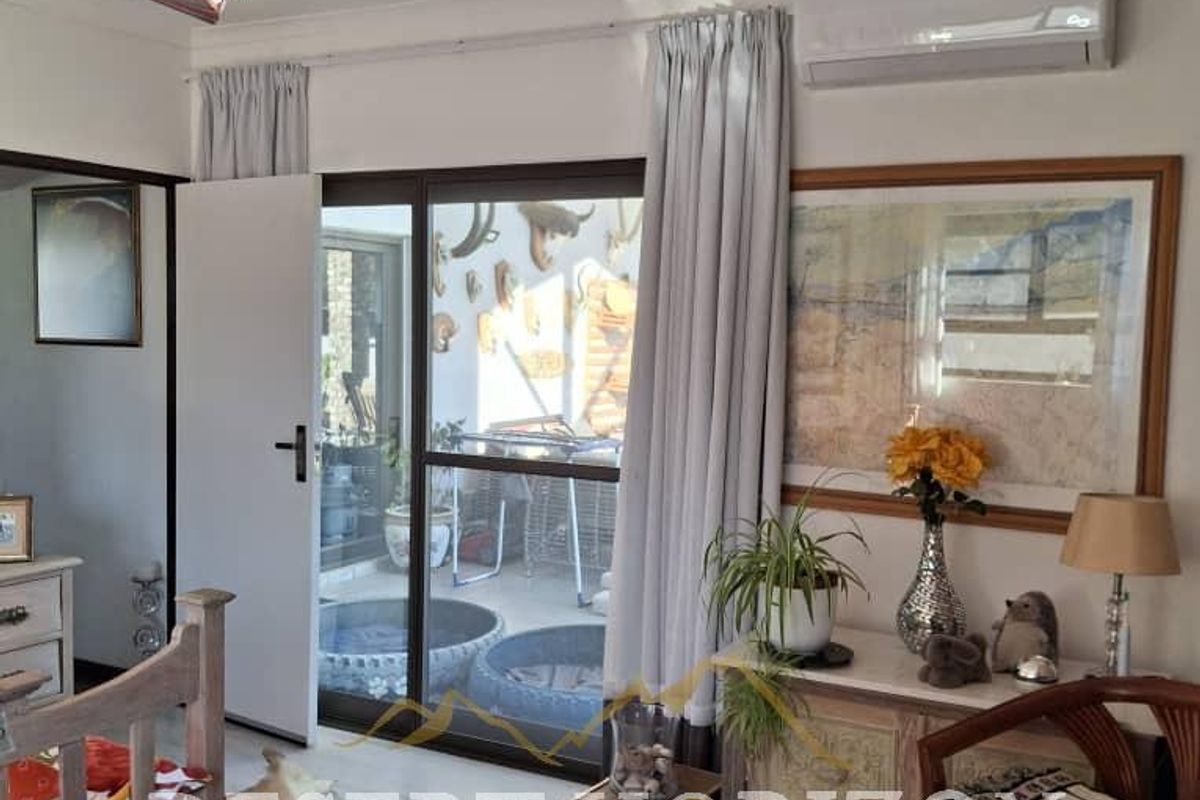 A bedroom featuring laminate flooring, a wall-mounted air conditioning unit, and a sliding glass door providing access to an outdoor area.