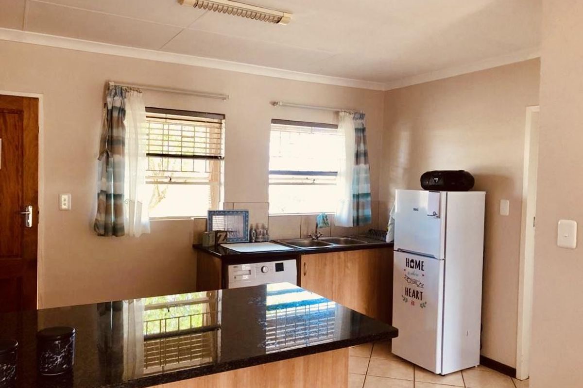 A functional kitchen featuring granite countertops, a double sink, and built-in cabinetry, offering a practical layout for daily meal preparation.