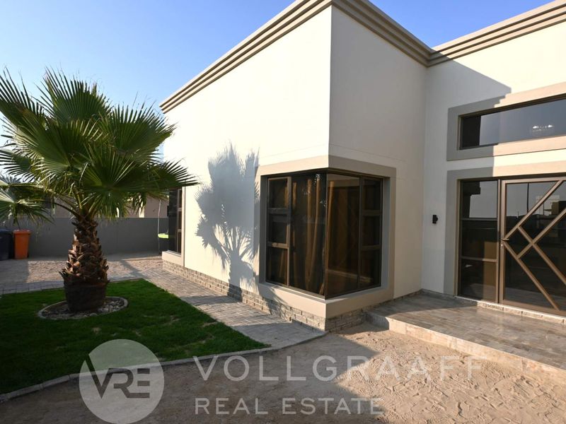 Rear exterior view of the property featuring modern stone cladding, a corner window, and a paved patio area.