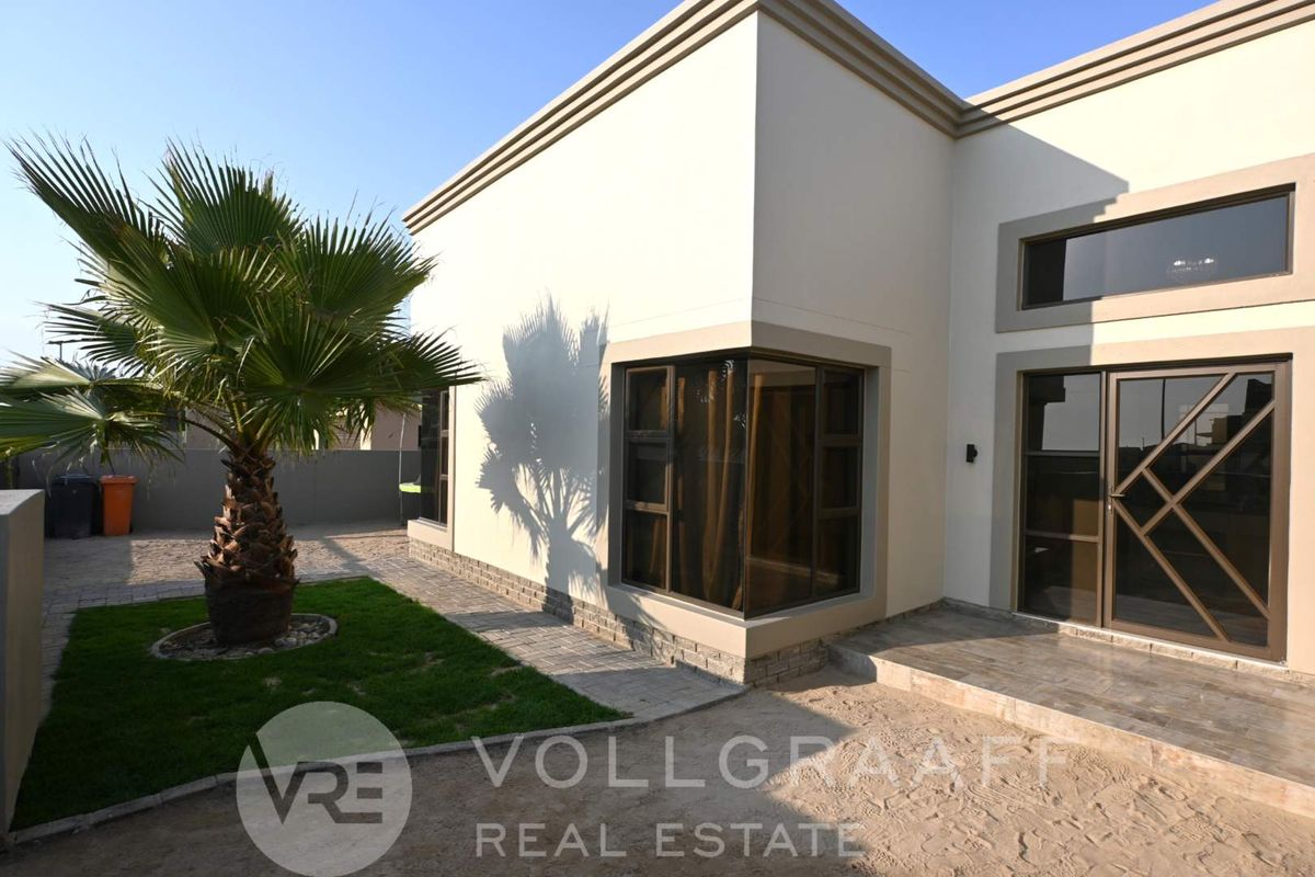 Rear exterior view of the property featuring modern stone cladding, a corner window, and a paved patio area.