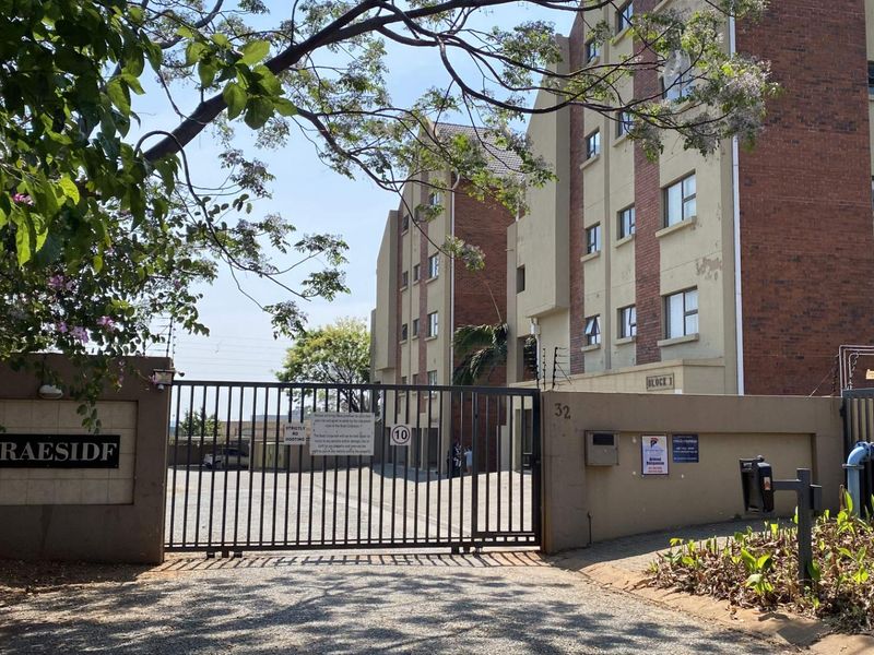 Front entrance view of Braesidf apartment complex featuring a secure gated access point, brick facade, and perimeter electric fencing.
