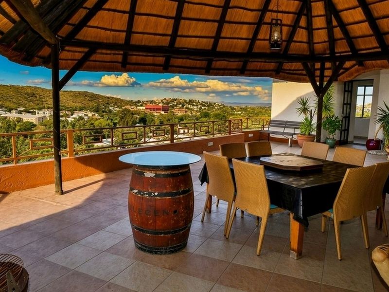 Spacious covered patio featuring a traditional thatched roof, tiled flooring, and panoramic views of the surrounding landscape.