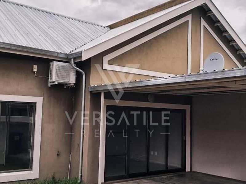 Rear view of the townhouse featuring a covered patio area, sliding glass doors, and an installed air conditioning unit.