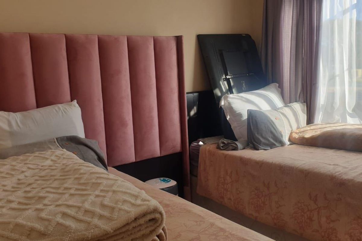 A bedroom featuring a pink upholstered headboard and natural light from the window.