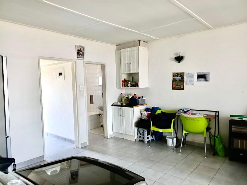 Open plan living area featuring tiled flooring, built-in cabinetry, and access to an adjacent bathroom, offering a functional layout with potential for modernization.