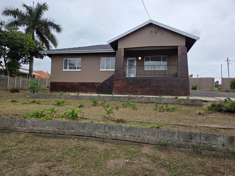 Front elevation of a single-story house featuring a brick-accented facade, covered porch, and terraced garden area with retaining walls.