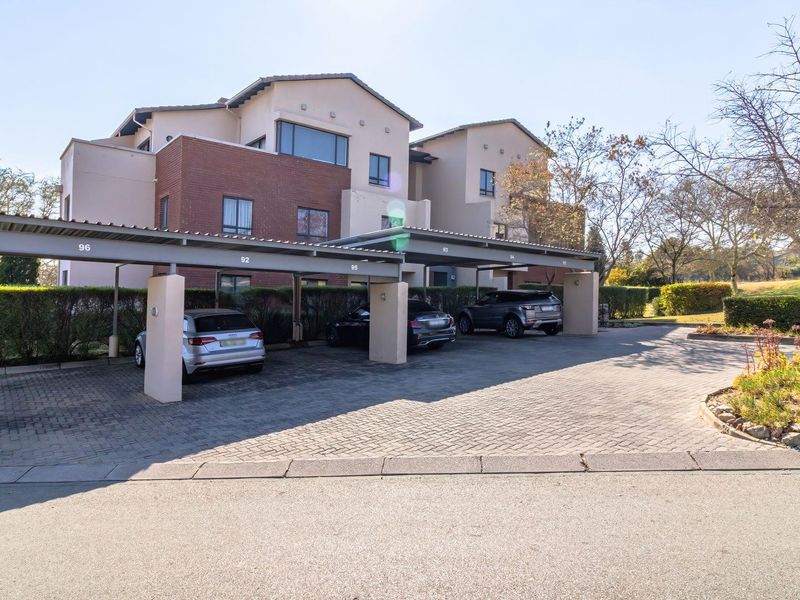 Exterior view of the apartment complex featuring a paved driveway and covered carport parking bays for residents.