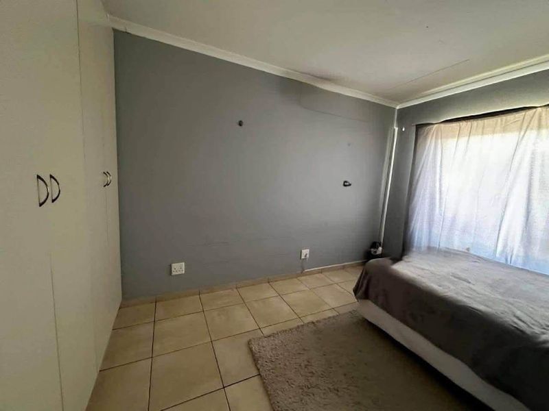 A bedroom featuring tiled flooring and built-in cupboards, offering a functional space ready for personalization and cosmetic updates.