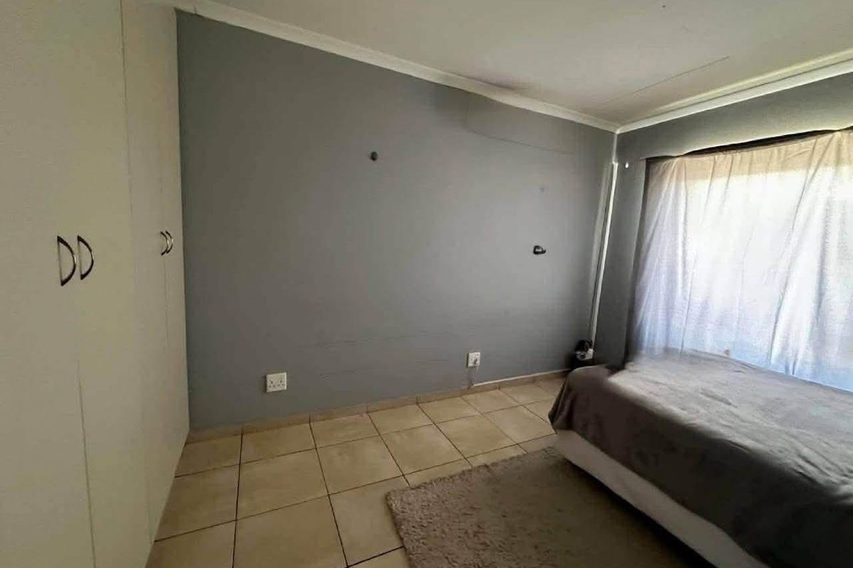 A bedroom featuring tiled flooring and built-in cupboards, offering a functional space ready for personalization and cosmetic updates.