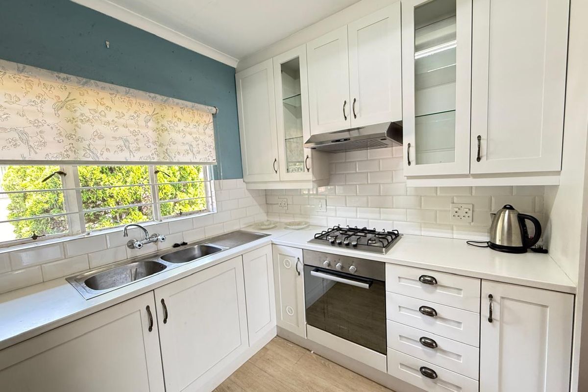 A well-maintained kitchen featuring white shaker-style cabinetry, subway tile backsplash, integrated gas hob, built-in oven, and a stainless steel double sink.
