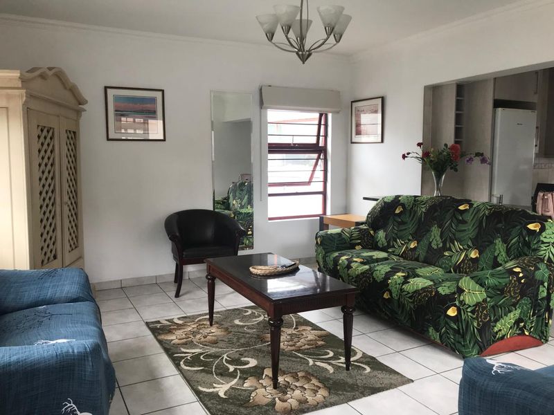 Open plan living area featuring tiled flooring, neutral walls, and a pass-through opening connecting to the kitchen space.