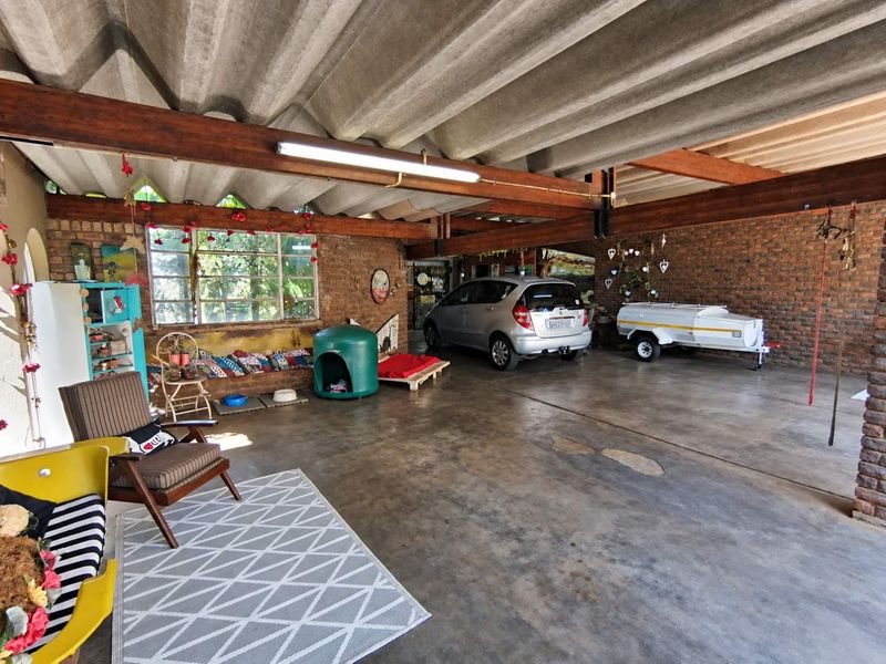 Spacious garage featuring exposed brick walls, timber beam ceiling, and concrete flooring, offering ample room for vehicle storage and utility use.