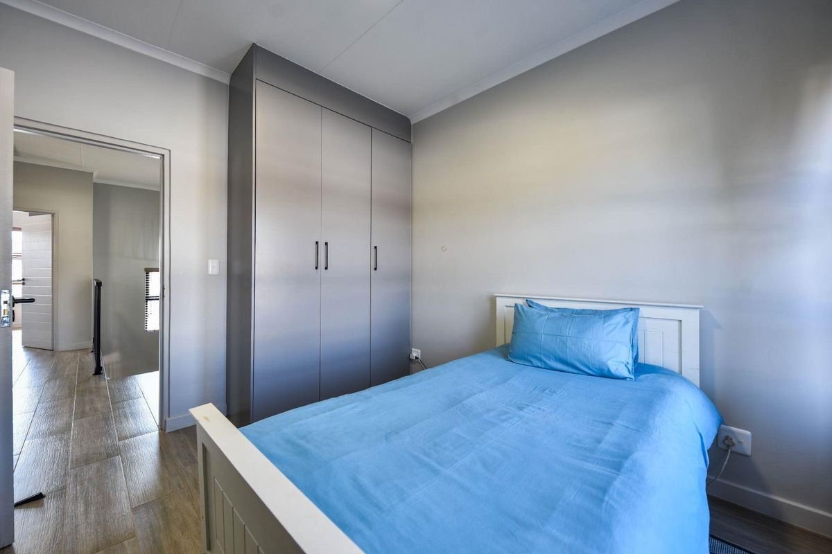 A well-maintained bedroom featuring neutral walls, tiled flooring, and a modern built-in wardrobe with sleek finishes.