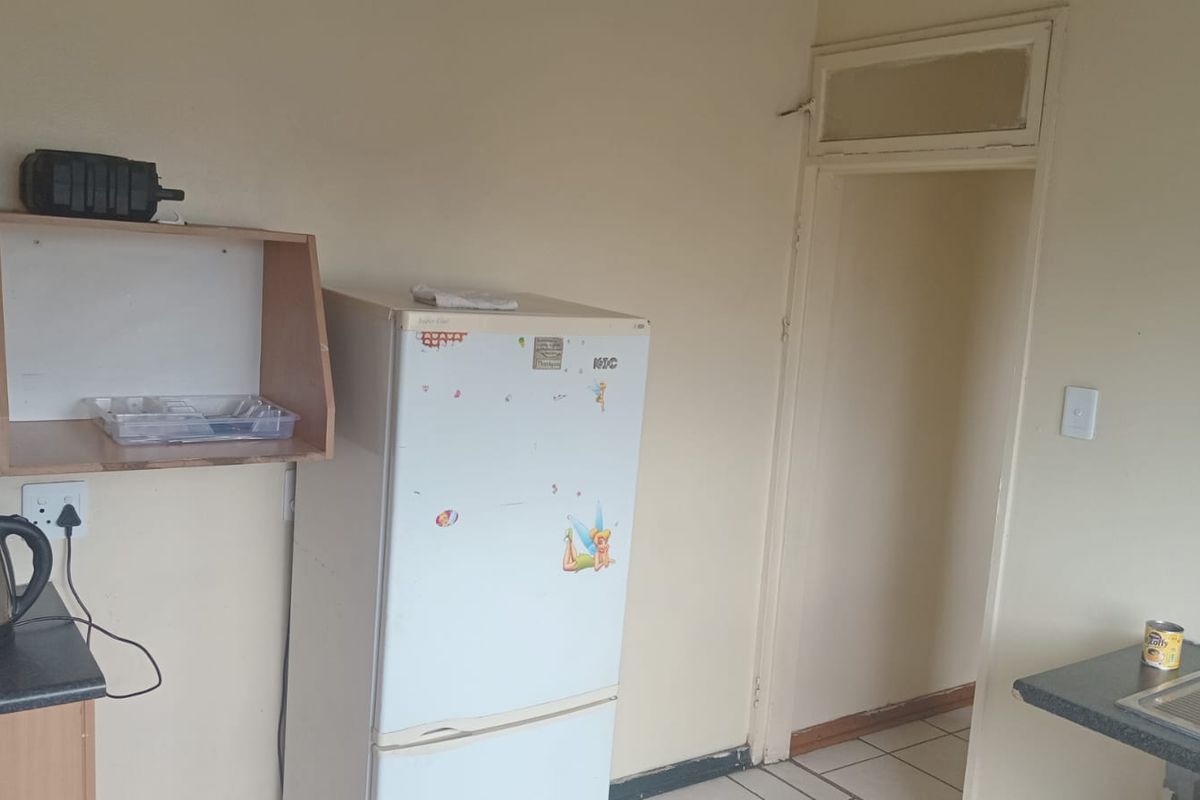 A functional kitchen area featuring basic cabinetry, tiled flooring, and a doorway leading to an adjacent room.