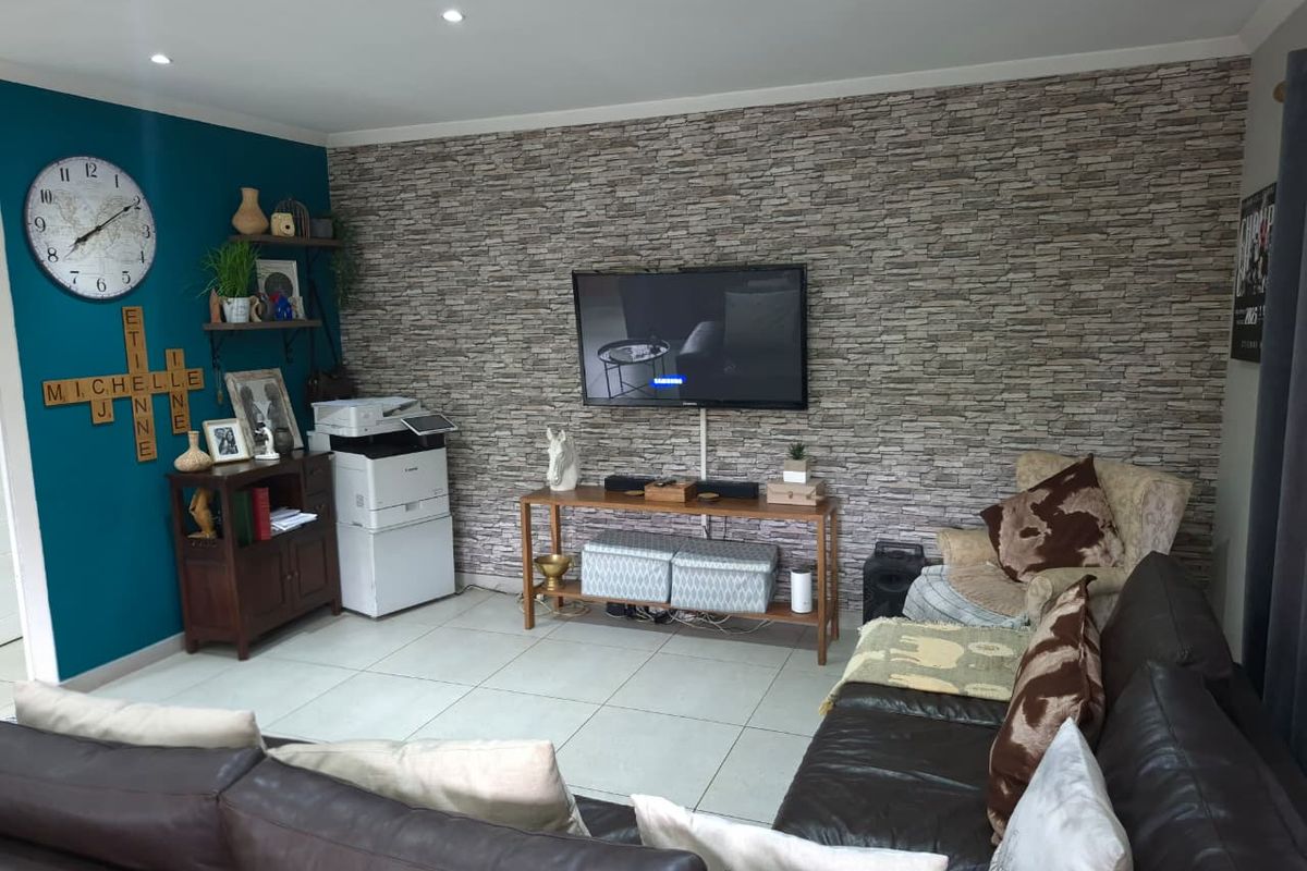 A living room featuring a stone-effect feature wall, tiled flooring, and recessed downlighting.