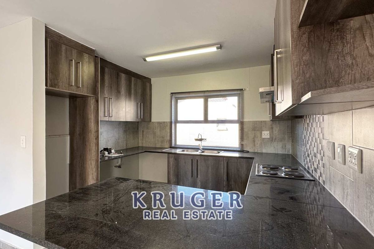 Modern kitchen featuring dark wood-look cabinetry, granite countertops, a built-in electric hob, and a double basin sink.