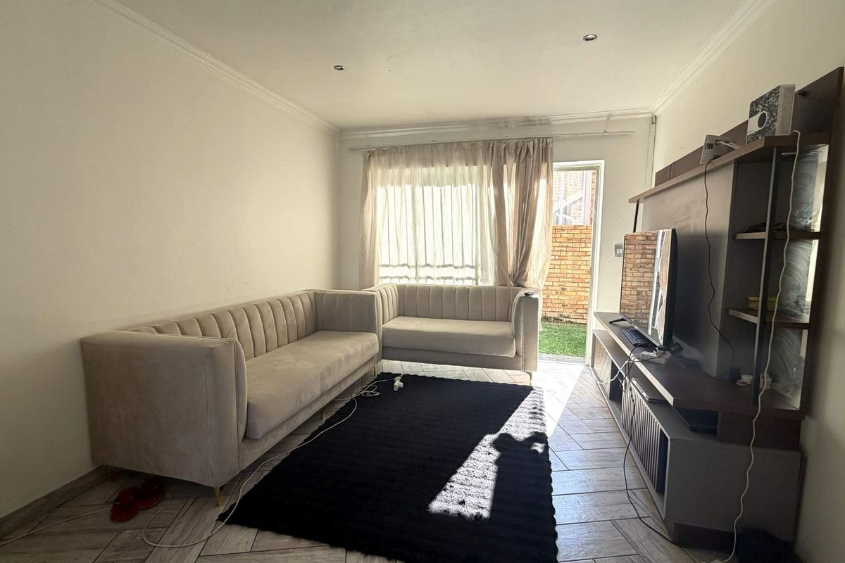 A living room featuring tiled flooring and direct access to an outdoor area through a glass door.