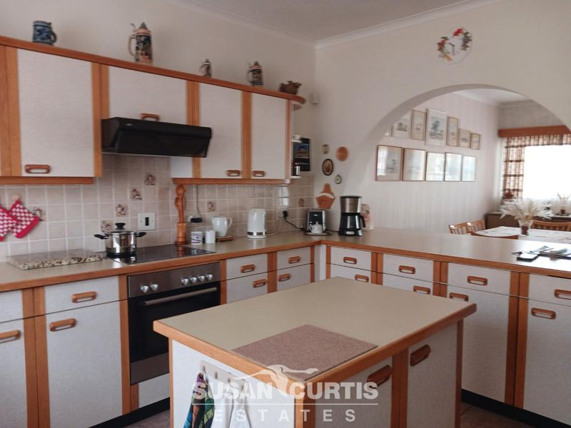 A functional kitchen featuring traditional cabinetry, a central island, and an open-plan layout connected to the dining area via a decorative archway.