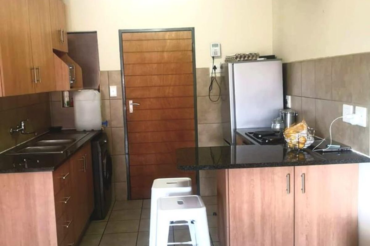 Functional kitchen featuring laminate cabinetry, granite countertops, tiled backsplash, and tiled flooring, providing a practical workspace with integrated hob and sink.