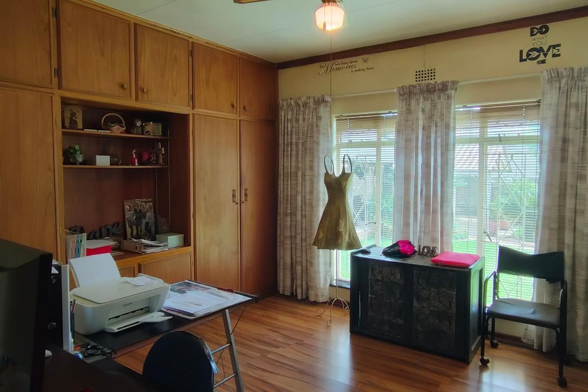 A bedroom featuring extensive built-in wooden cabinetry, laminate flooring, and large windows with security bars, offering ample storage and natural light.