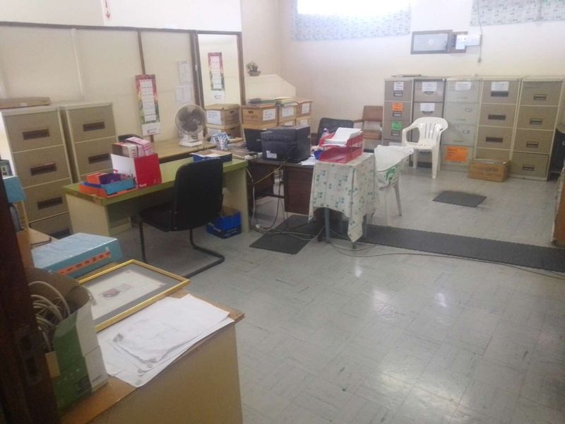 A functional office space featuring vinyl tile flooring and partition walls, currently utilized for administrative storage and workspace.