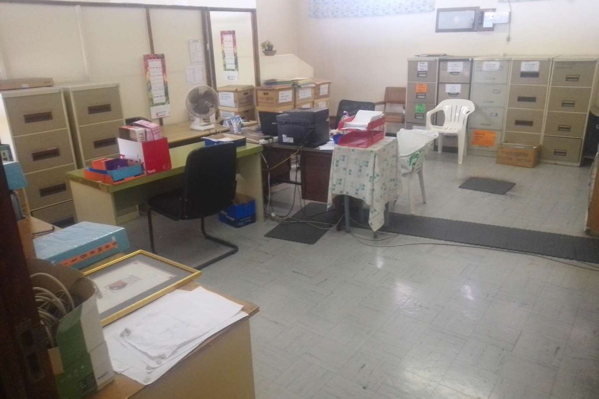 A functional office space featuring vinyl tile flooring and partition walls, currently utilized for administrative storage and workspace.