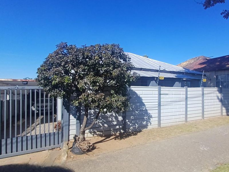 Front view of the property featuring a precast concrete boundary wall, metal sliding gate, and electric security fencing.