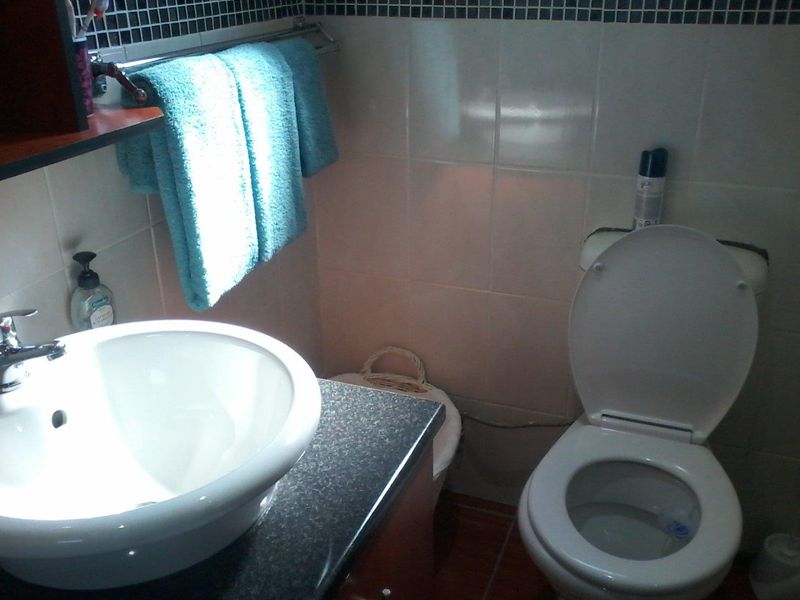 A compact bathroom featuring a vessel sink on a dark vanity countertop, a standard toilet, and tiled wall finishes.