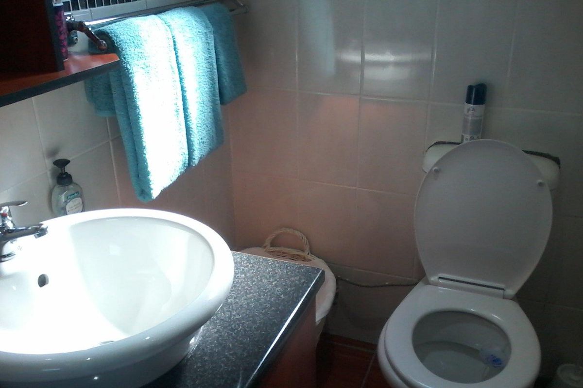 A compact bathroom featuring a vessel sink on a dark vanity countertop, a standard toilet, and tiled wall finishes.