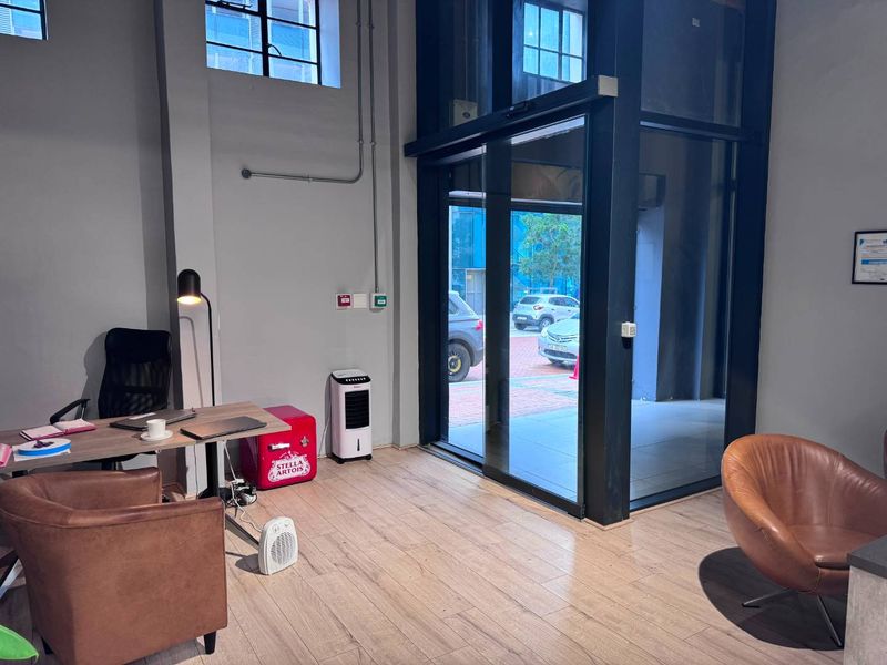 Modern commercial entry area featuring high ceilings, large glass sliding doors, and durable laminate flooring, providing a bright and professional welcome space.