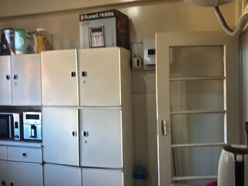A dated kitchen area featuring built-in cabinetry, a tiled splashback, and a glass panel door, offering potential for modernization and renovation.