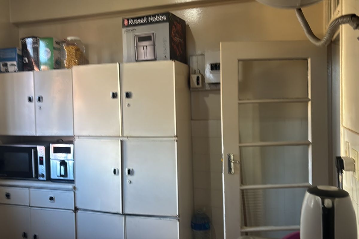 A dated kitchen area featuring built-in cabinetry, a tiled splashback, and a glass panel door, offering potential for modernization and renovation.