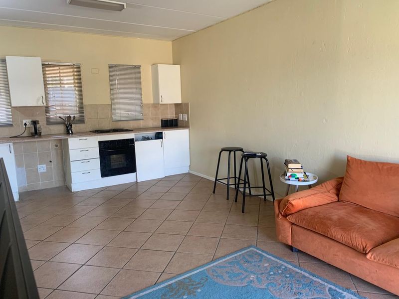 Open plan living and kitchen area featuring tiled floors, built-in cabinetry, and integrated oven and hob, requiring cosmetic updates to improve overall condition.
