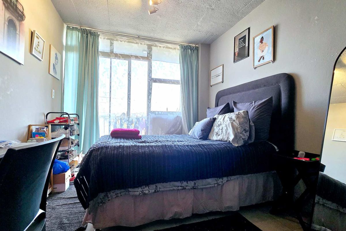 A bedroom featuring a large sliding glass door providing natural light and access to an outdoor area, with a textured ceiling finish.