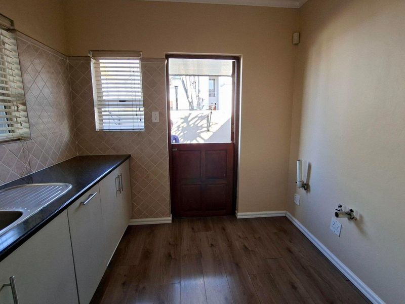 A functional laundry room featuring built-in cabinetry, a stainless steel sink, laminate countertops, and dedicated plumbing connections for appliances.