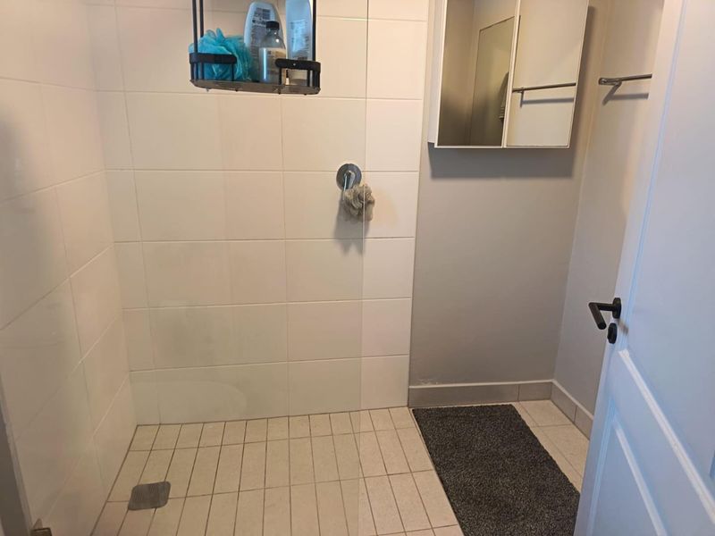 A functional bathroom featuring a walk-in shower with tiled walls, a tiled floor, and a wall-mounted medicine cabinet.