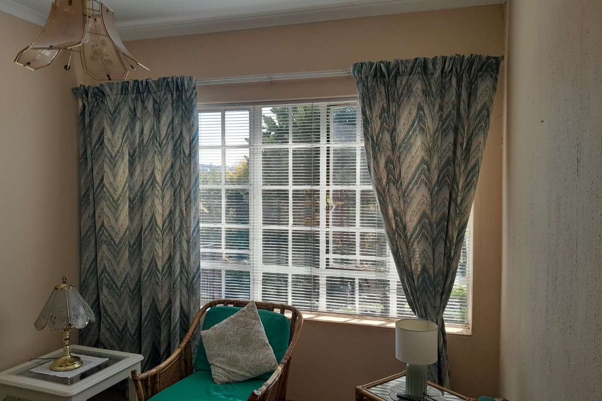 A living room area featuring a large window with grid detailing, providing natural light and a view of the exterior.