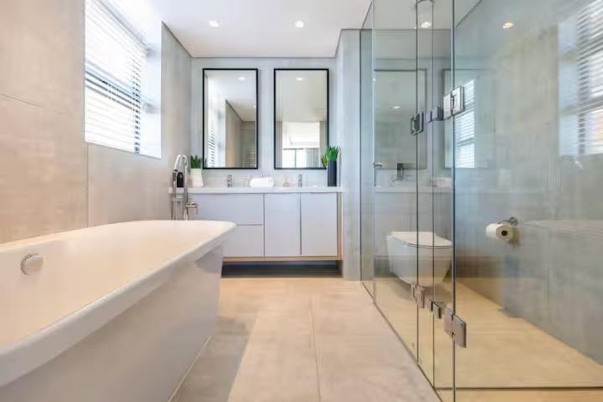 Modern bathroom featuring a sleek freestanding bathtub, double vanity with wall-mounted mirrors, and a spacious glass-enclosed shower with high-end finishes.