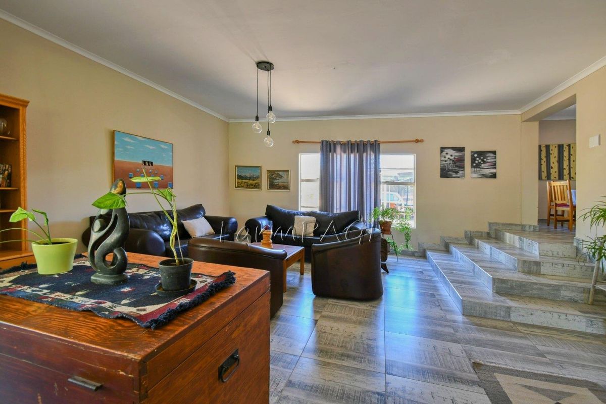 Spacious living area featuring tiled flooring, a raised platform section, and large windows allowing for natural light.