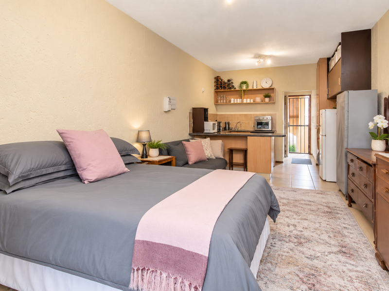 Open-plan studio apartment featuring a combined bedroom and kitchenette area with tiled flooring and direct access to an exterior entrance.